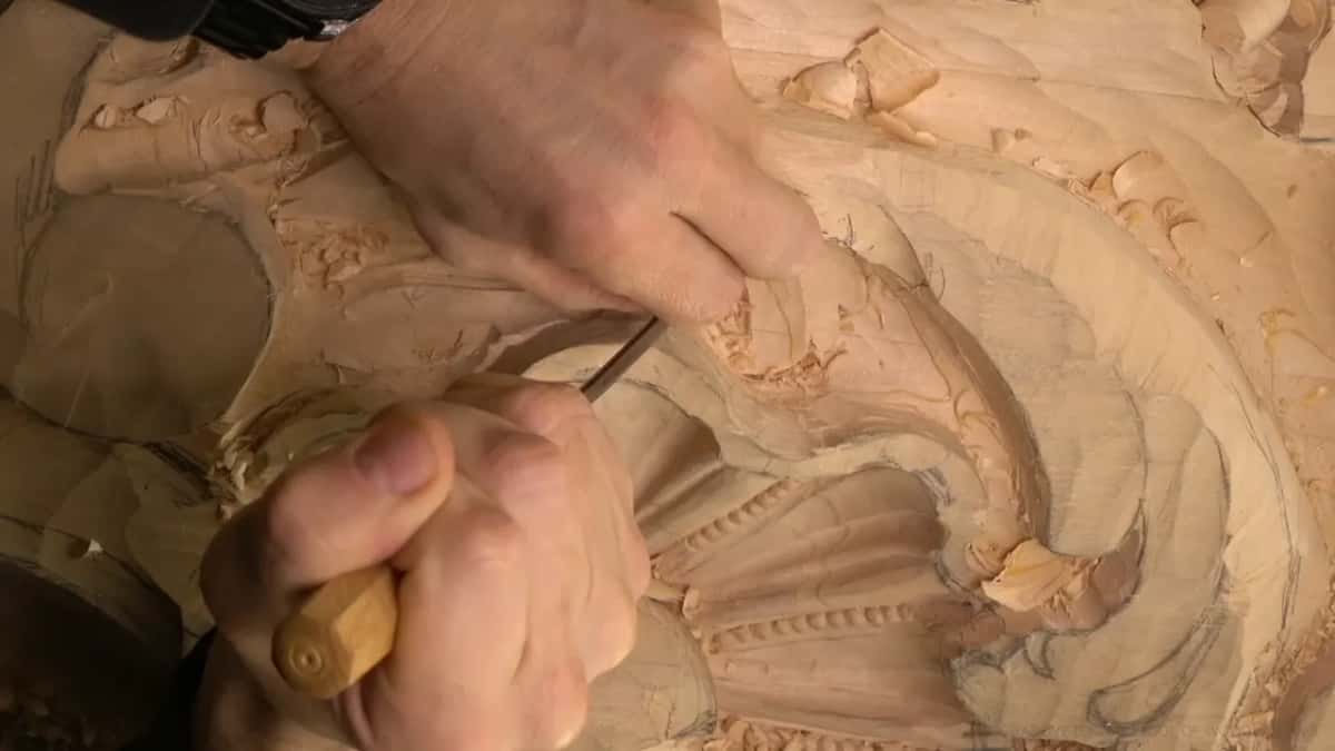 A fist wraps an eight sided handle while the other hand steadies it above the beaded shell.