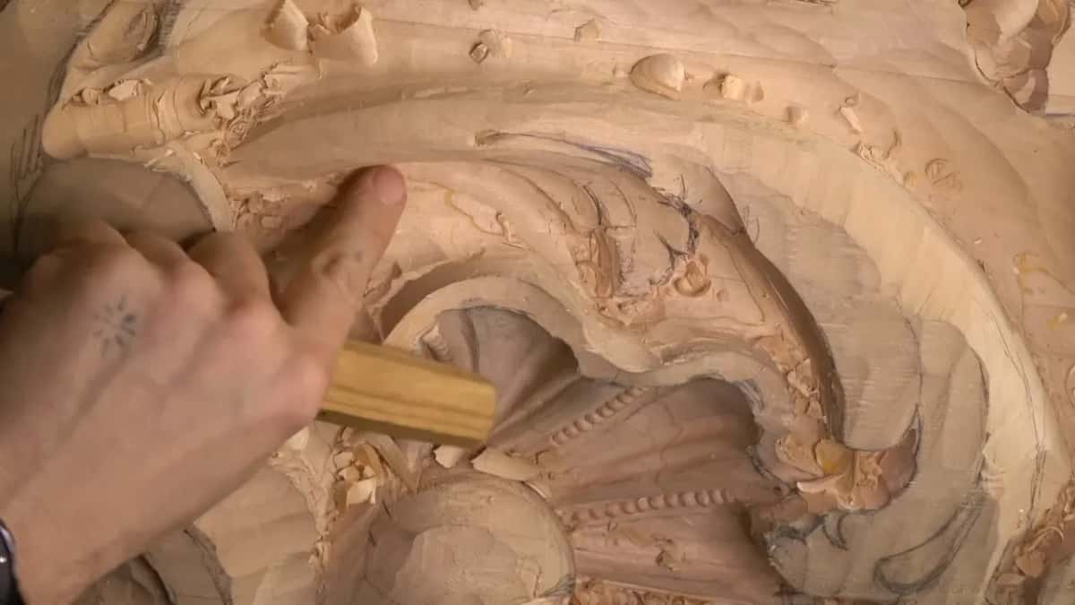 A hand grips a flat, pale handle close to the ribbed shell.