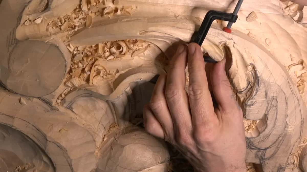 A small black clamp squeezes the glued piece, fingers holding it in place.