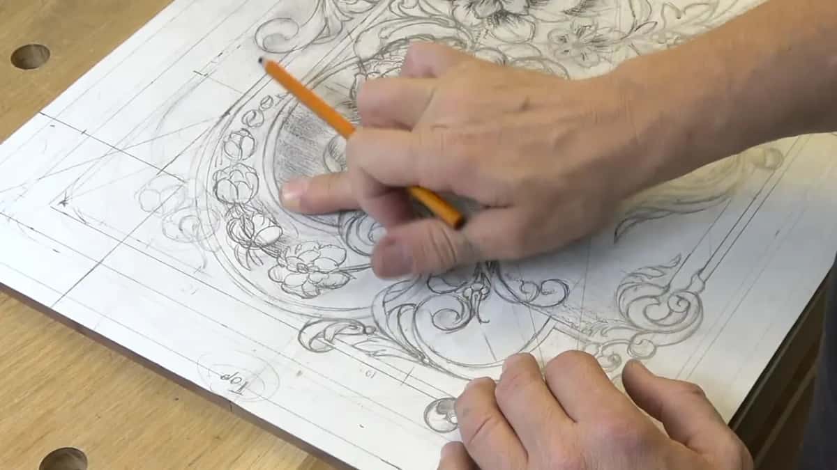 Both hands on the board, the left one holding it steady and the right one smudging the ground behind the bouquet