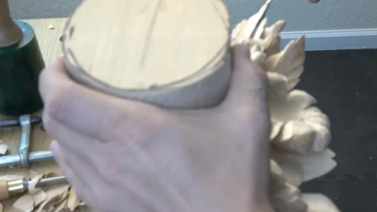 Both hands lowering the blank toward its socket.