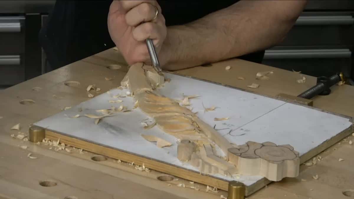 Seen from above, one hand drives a gouge around the outside of the volute.