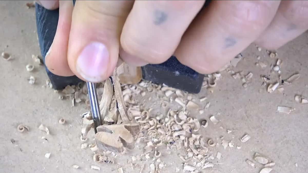 Seen from above, a small gouge works down between the parts while a thumb holds them still.