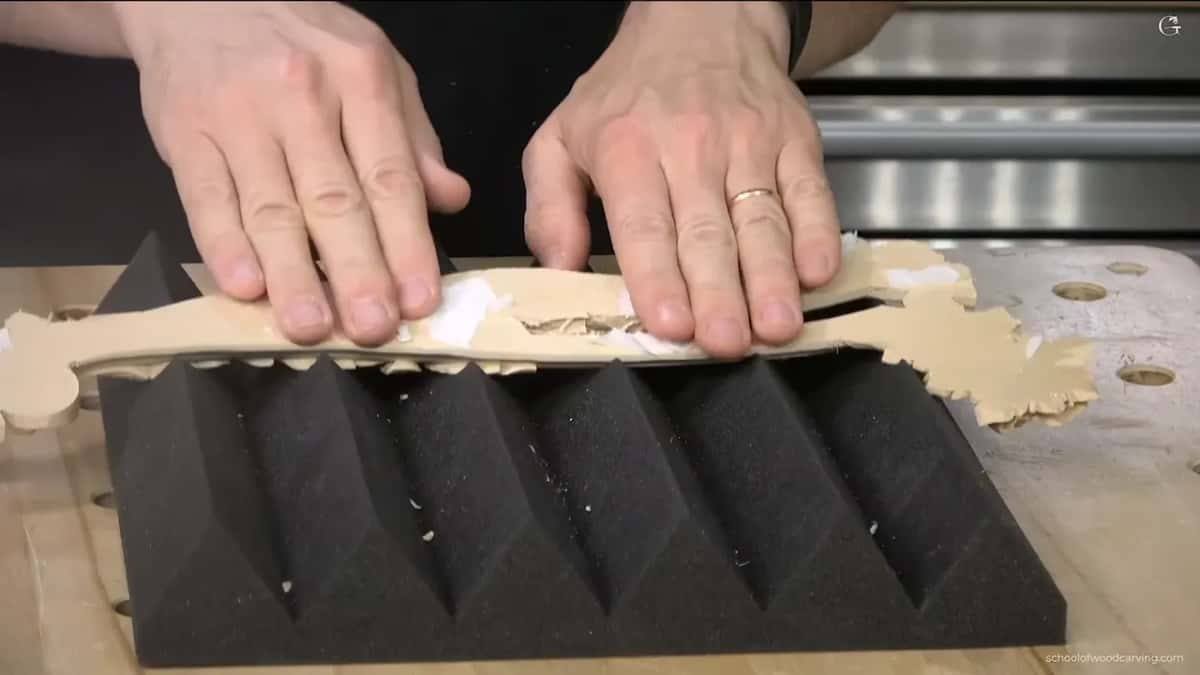 Hands pressing the finished face down into ribbed black foam so it takes the shape.