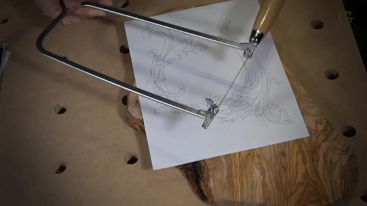 Fretsaw frame laid across the printed design on the slab, a saw that cost about twenty dollars