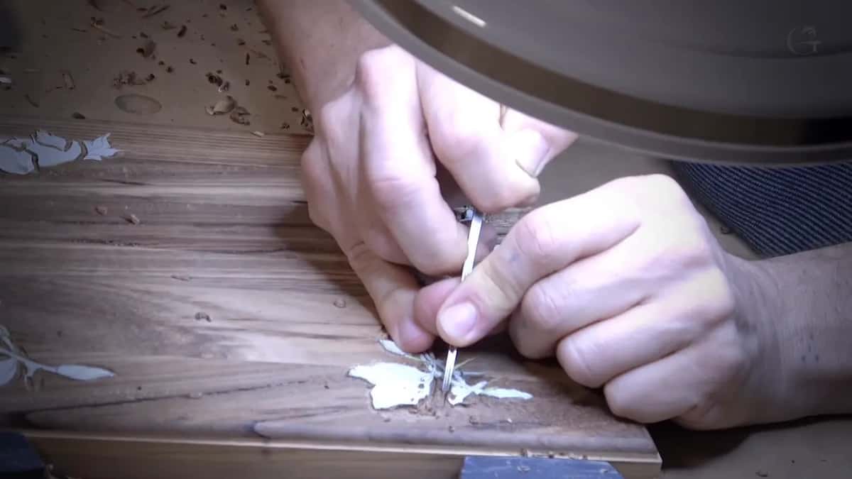 Small leaves being carved straight into the acacia lid, paper pattern and all