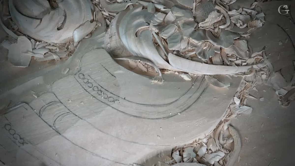 Row of small circles drawn in pencil where the beads will be carved, with the scroll already shaped above