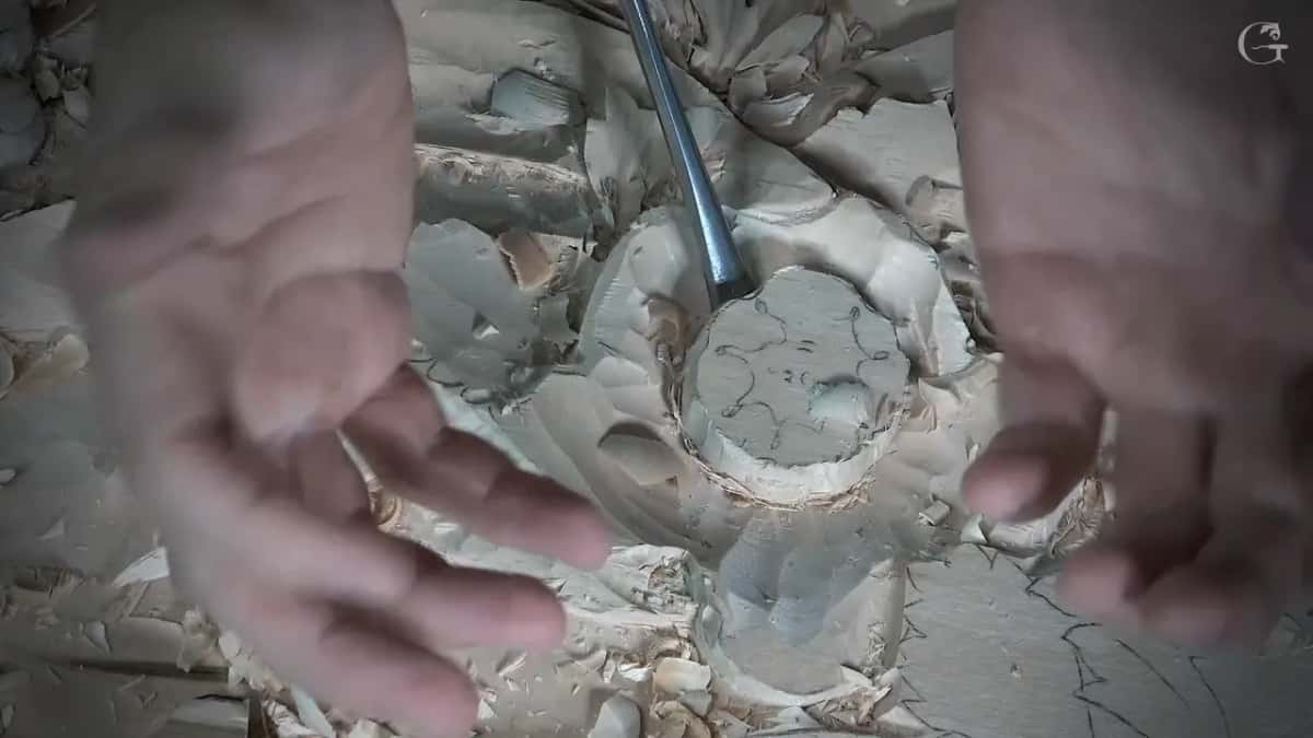 Tip of the gouge set into the round flower centre while both hands frame it, slightly out of focus