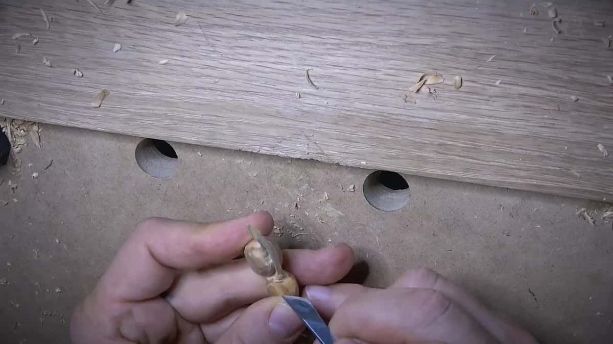 Knife point at the joint, one olive held upright between the fingers