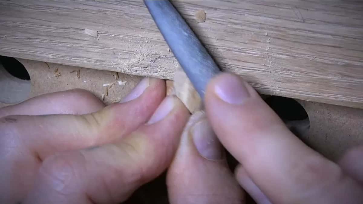 Rasp rounding an olive held against the oak, fingers wrapped around the cluster