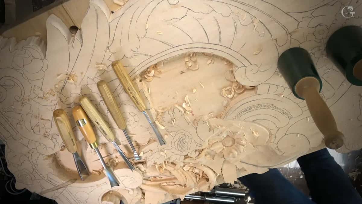Five gouges and two mallets laid across the panel