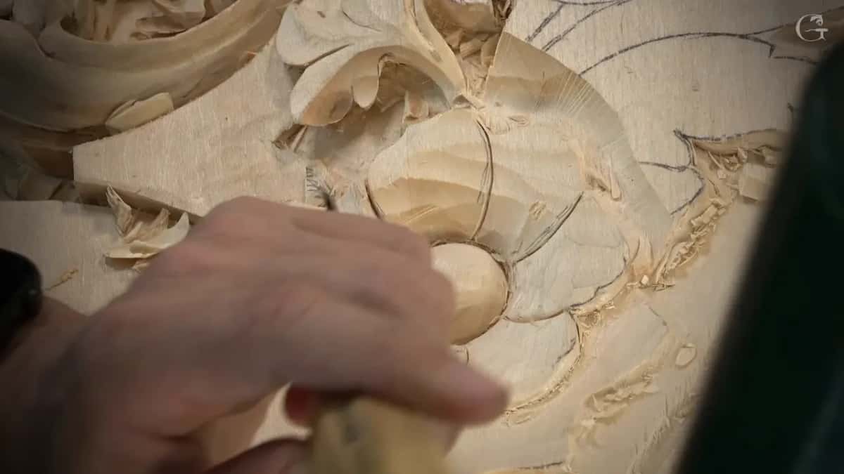 Palm resting on the domed flower while the other hand holds a gouge just out of the frame