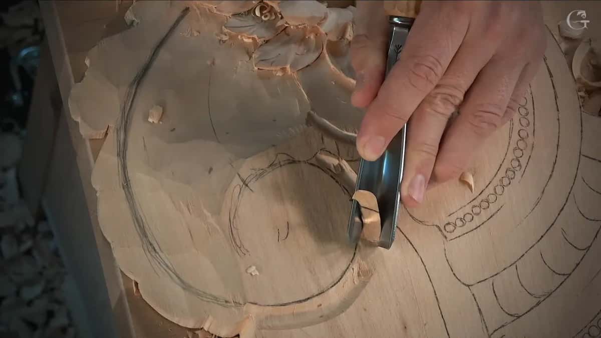 Gouge lifting a single shaving directly off a pencil line, the rest of the design still untouched beside it