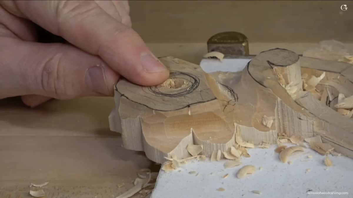 Fingers steady the rosette while a narrow blade works away at its middle.