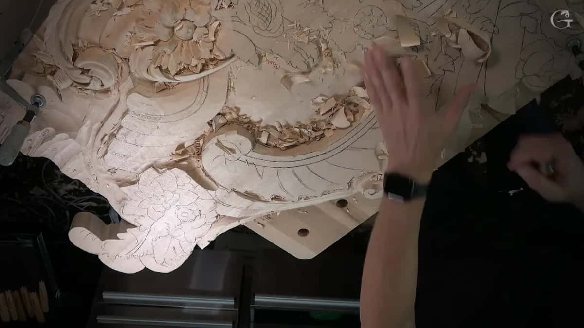 Chips falling from the panel as one hand lifts clear of the carving