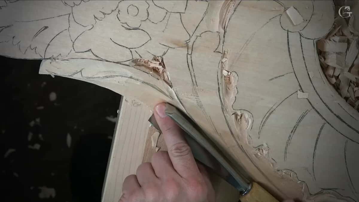 Fingertip pressed against the blade of the gouge for control while the edge sits right at the turn of the drawn line