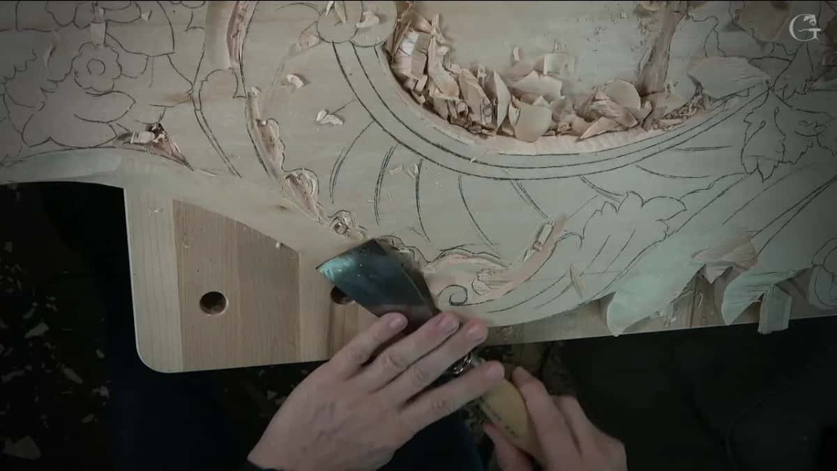 Wide flat chisel held in both hands against the panel