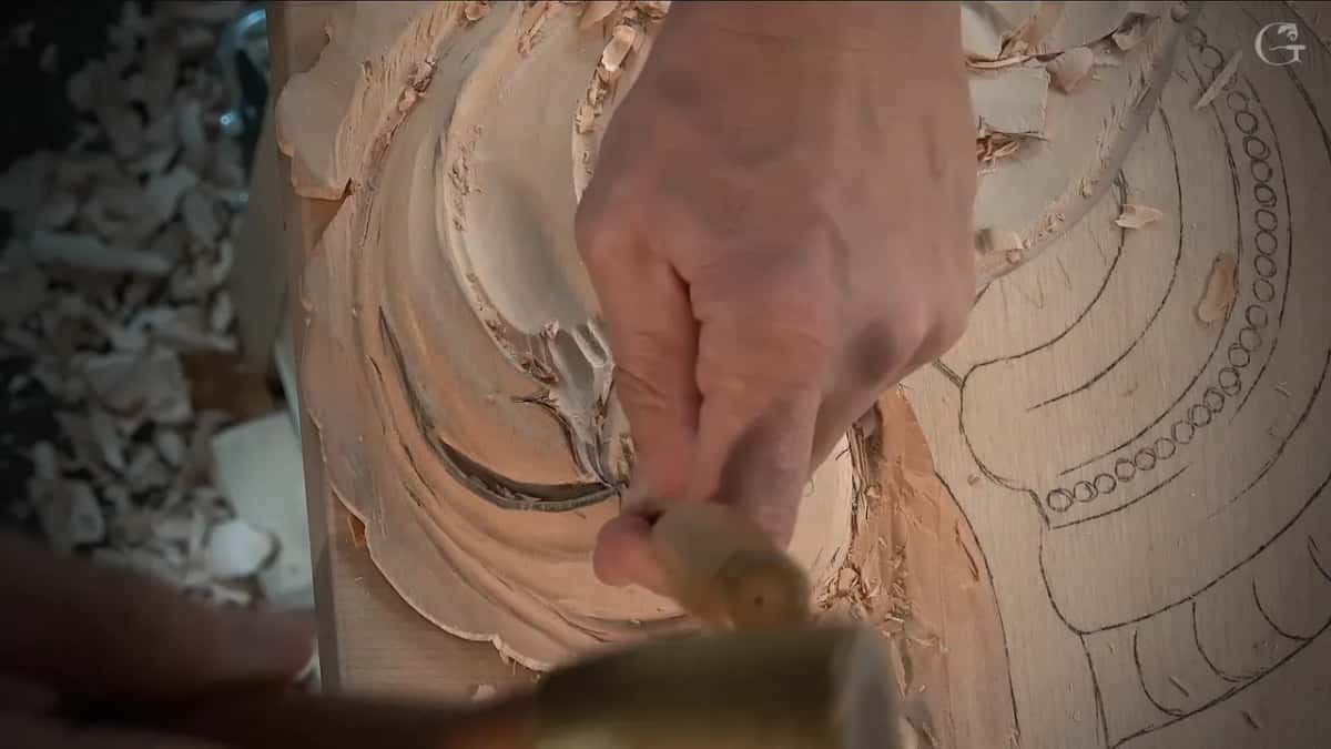 One hand drives the gouge into the curl