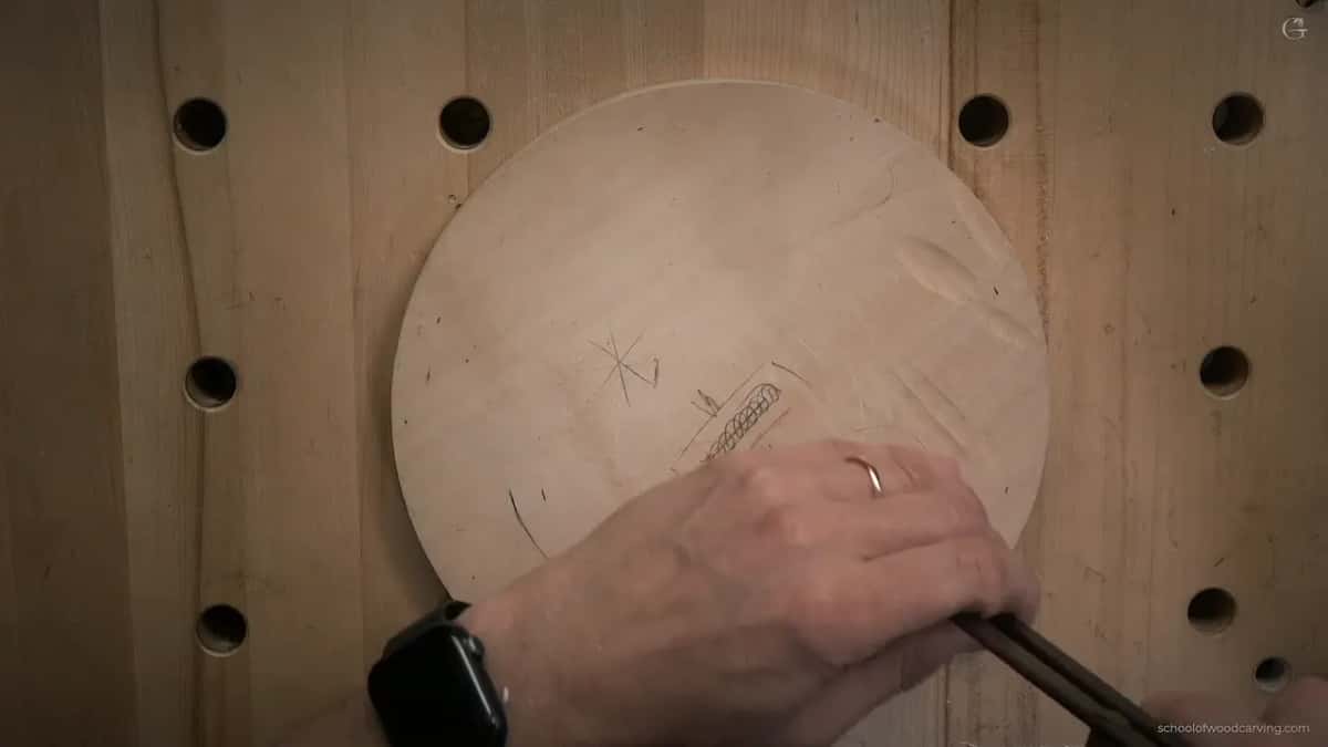 Underneath, the plate shows a compass star, a small carved braid and a hand gripping calipers