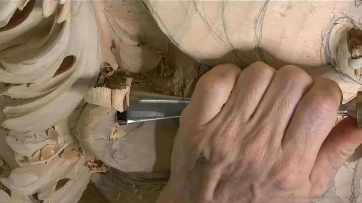 One fist pushes a gouge sideways, and a thick chip curls up.