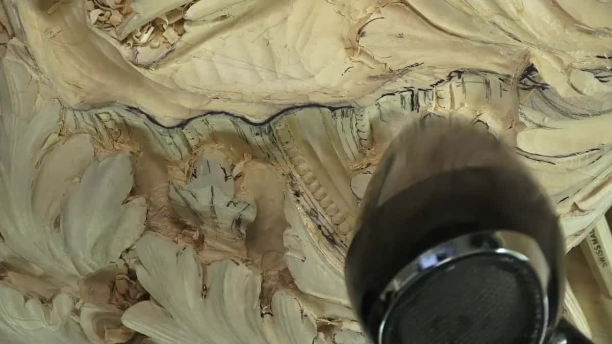 Hair dryer nozzle pointed down into a carved hollow beside a dark line