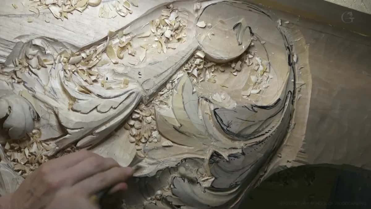 Low light over the scroll as one hand clears the hollow.