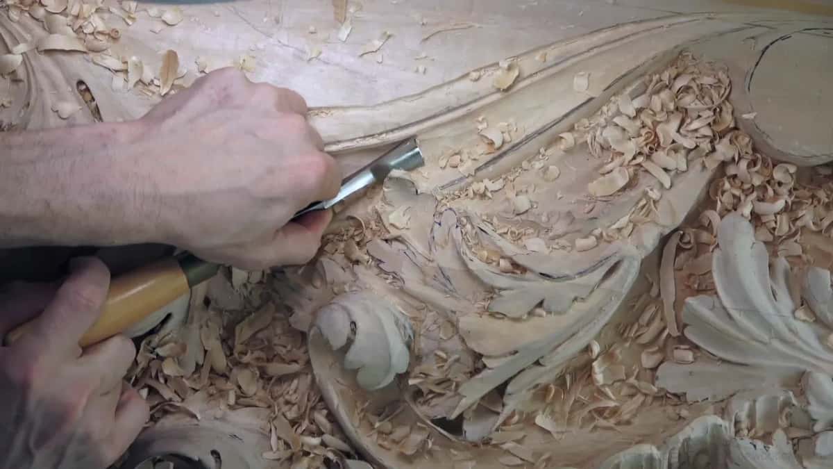 A yellow handle sits low while the blade works in the hollow beside the carved leaves.