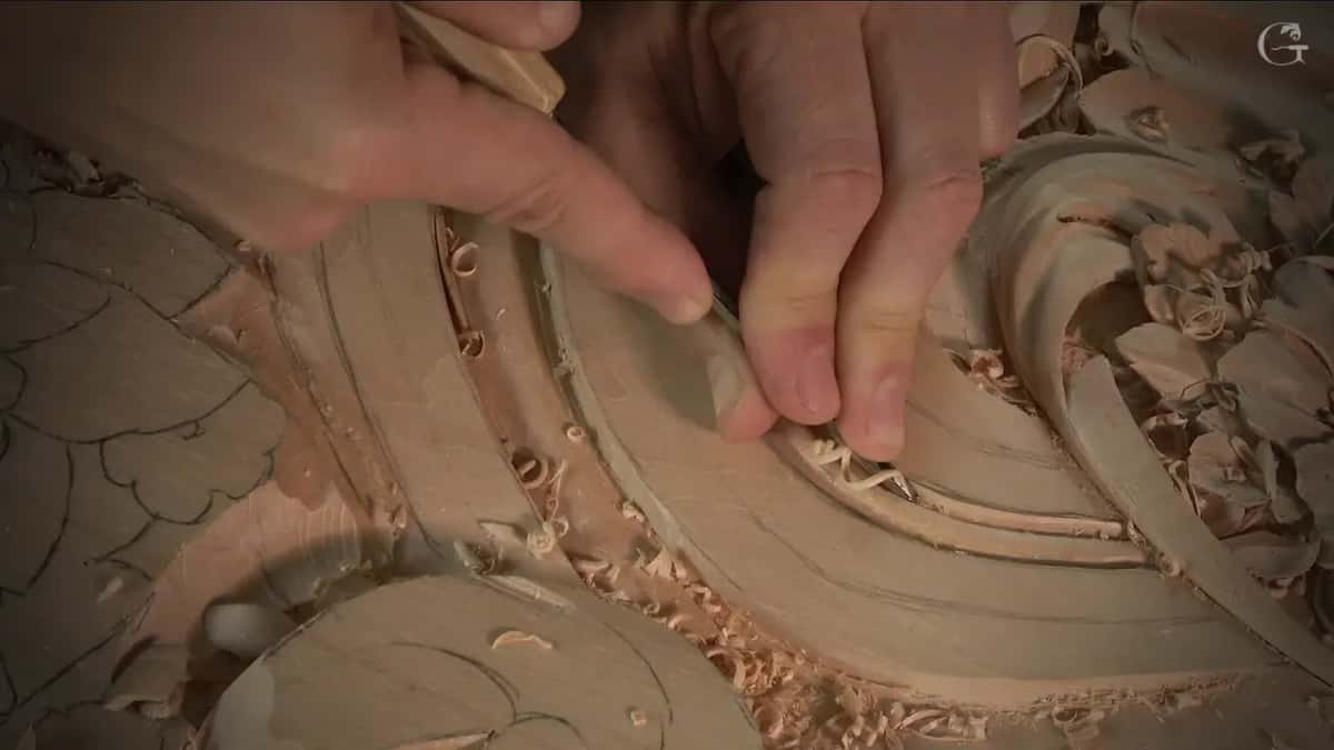 Fingers push the small gouge on and a thin curl of wood rises in front of it