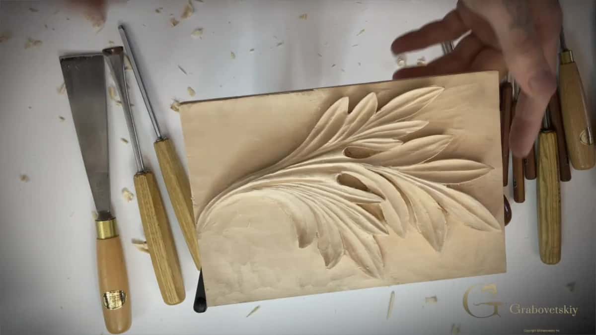 The finished leaf on the white bench, gouges laid out along one side.