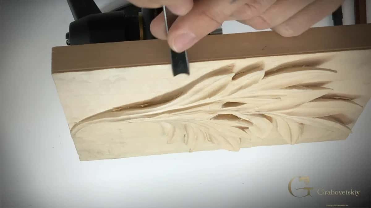 A V tool cleaning the corner where ground meets carving.