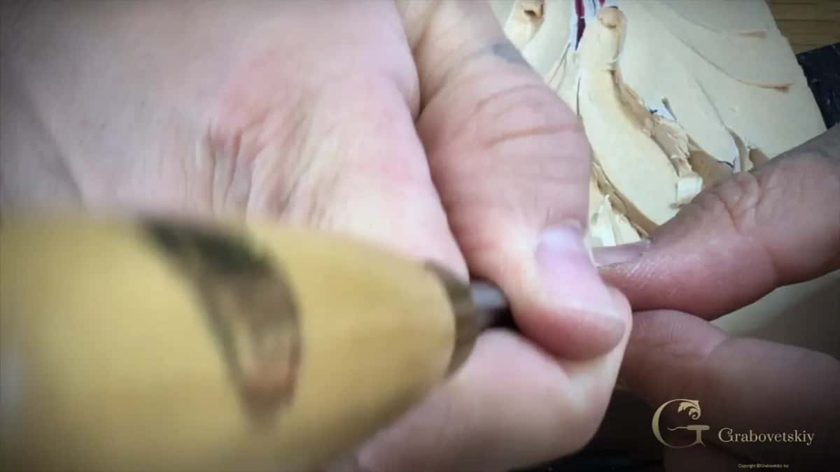 Soft focus, a boxwood handle filling the frame while the hand rolls it through the cut.