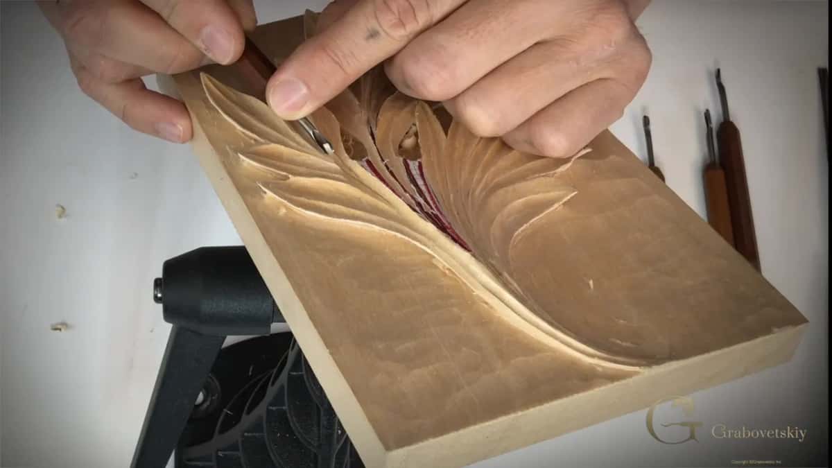 Both hands bring a very small gouge down onto the leaf.