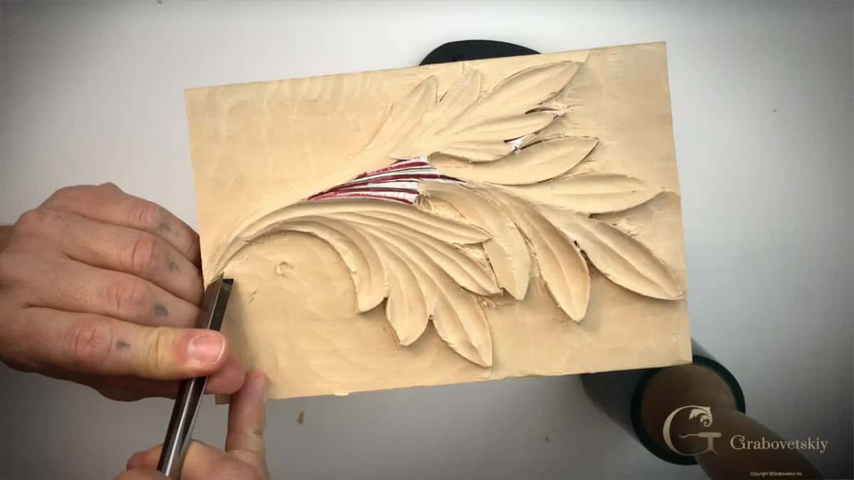 Both hands bring a round shafted tool up against the edge of the leaf.