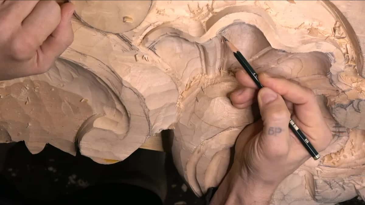 Near its tip, a pencil marks the bead spacing along one curved rib, a short tick at a time.