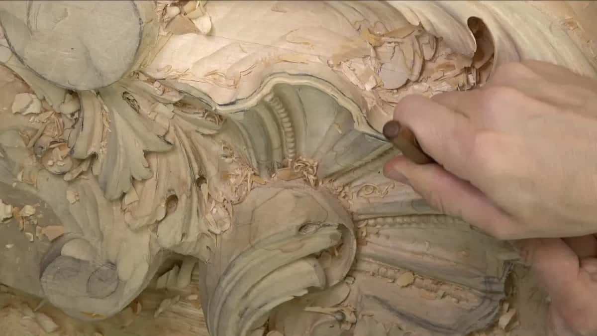One hand holds a short dark handle low against the beaded shell's lip.