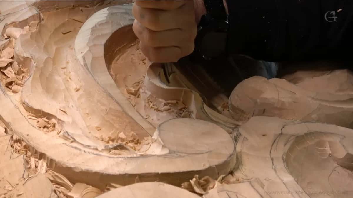Close view of a deep scrolled hollow, its walls carved in long facets and chips still sitting inside.