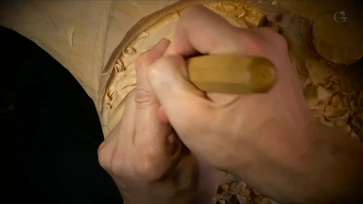 Knuckles and a yellow handle pressing into a rounded form.