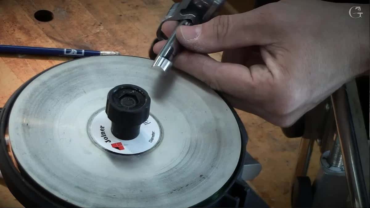 Hand brings a small blade down onto the pale spinning disc