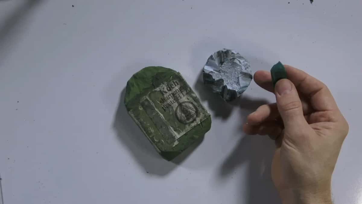 Same two compounds on white, a finger resting on the green Koch sharpening block
