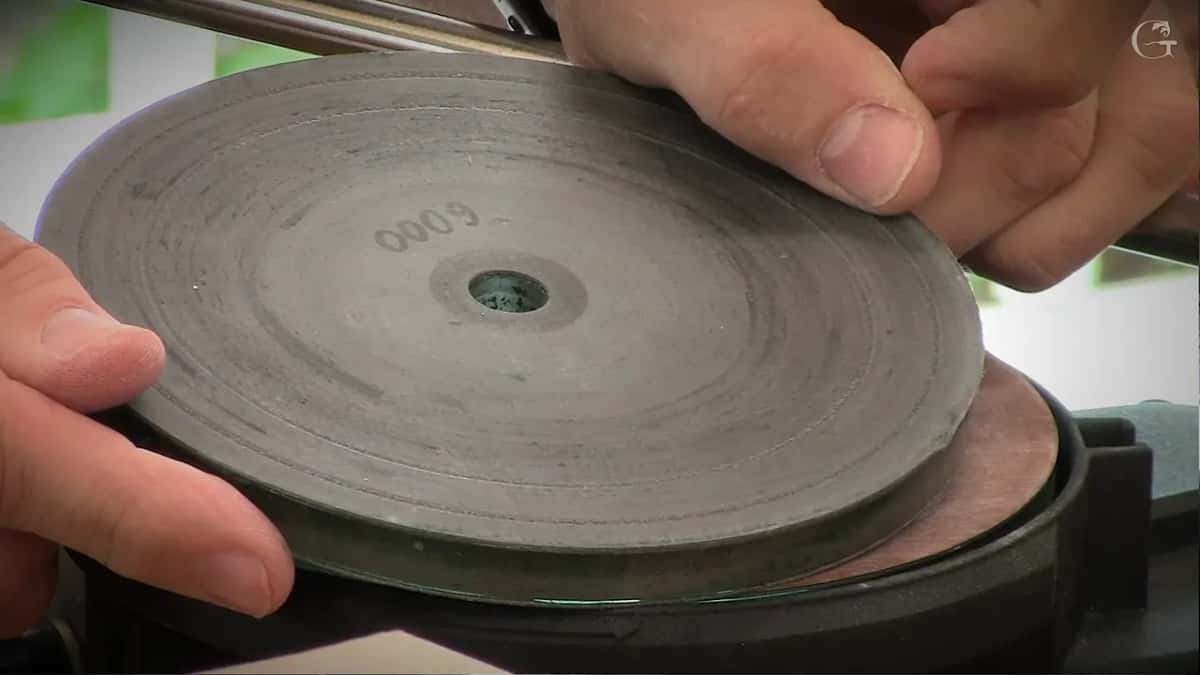 Two hands lift a large grey disc stamped six thousand off the machine, a second disc still waiting on the hub underneath