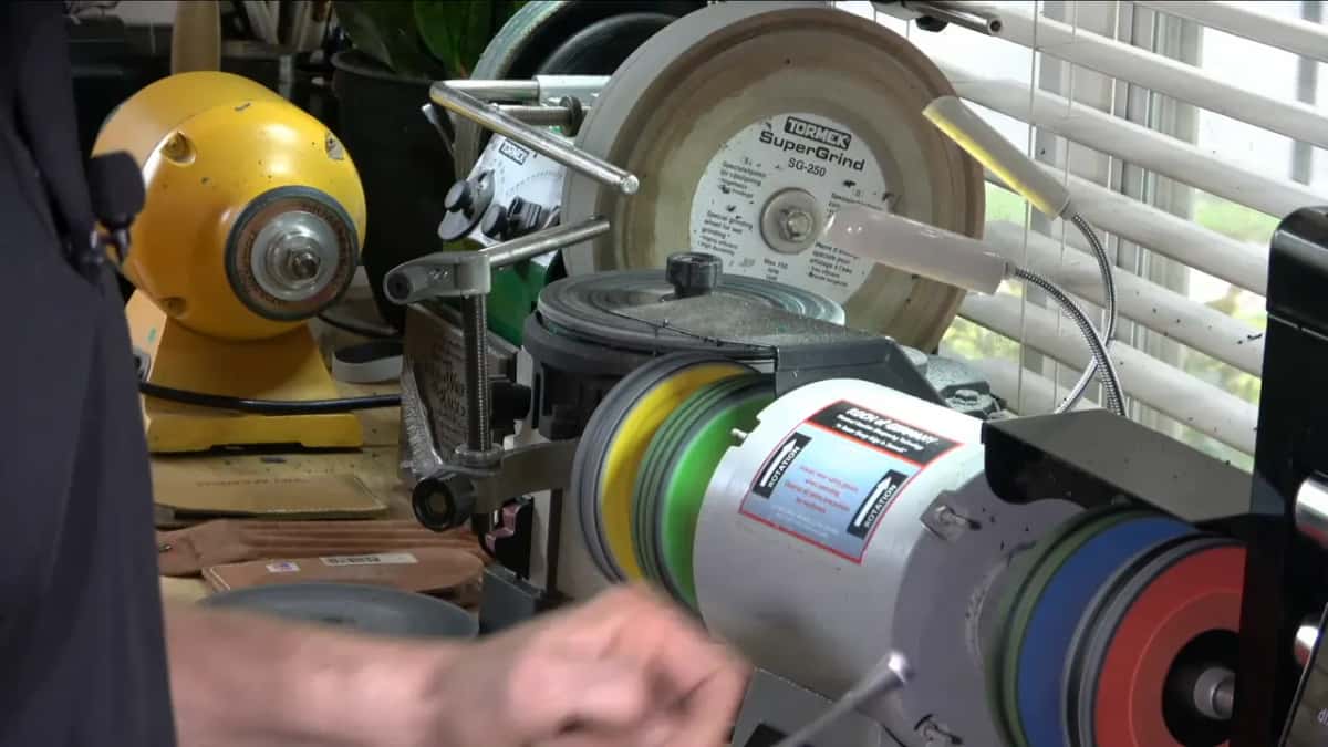 Whole sharpening bench: a yellow buffer, a Tormek SuperGrind wheel, and stacks of colored buffing wheels