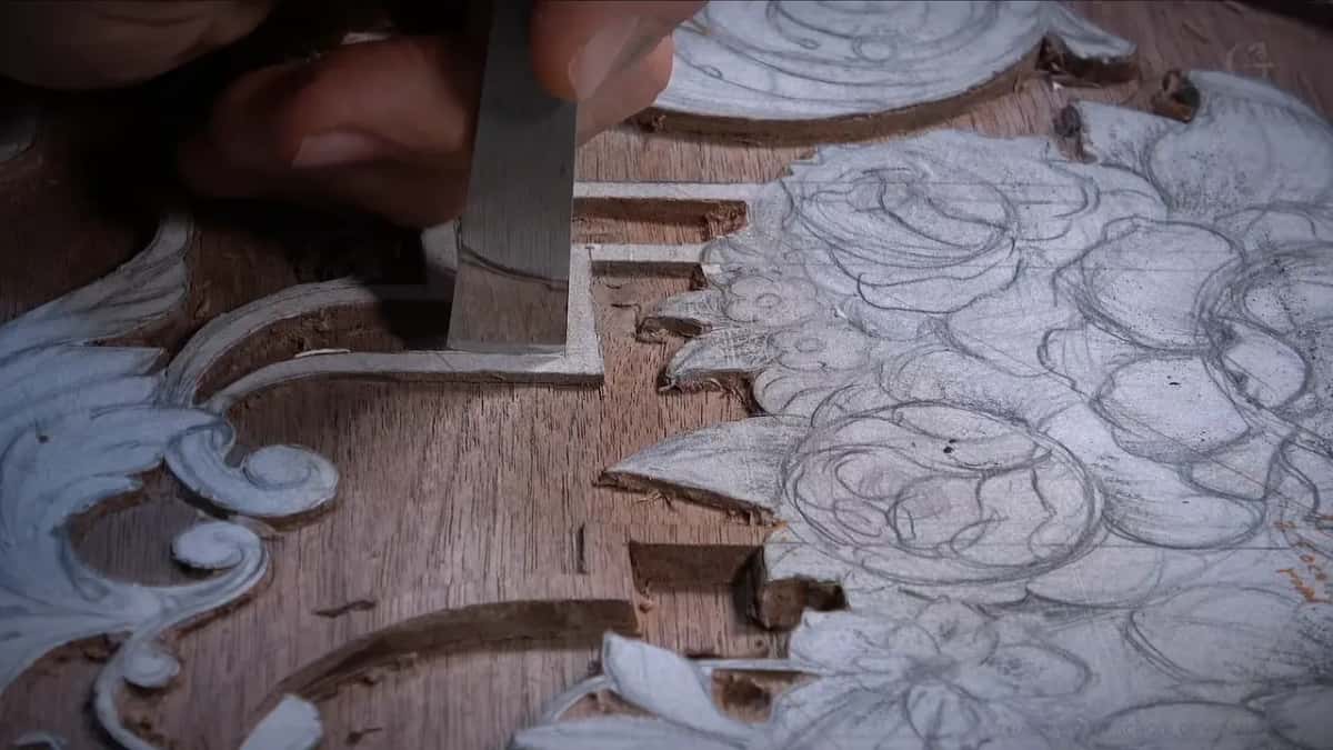 On a dark board a flat chisel stands straight up against the wall, with penciled flowers beside it.
