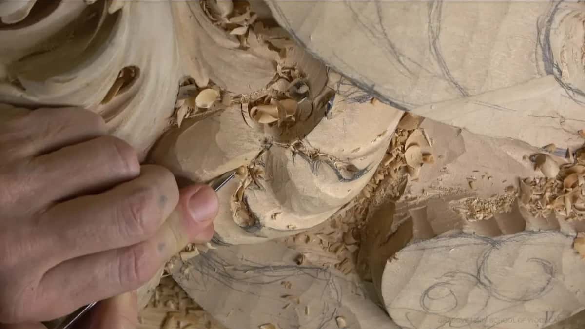 Fingertips pinch a very thin tool into a tight spot where two lobes meet.