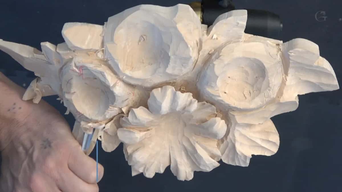 Forearm along the edge of the panel, a slim metal pencil held against the left flower