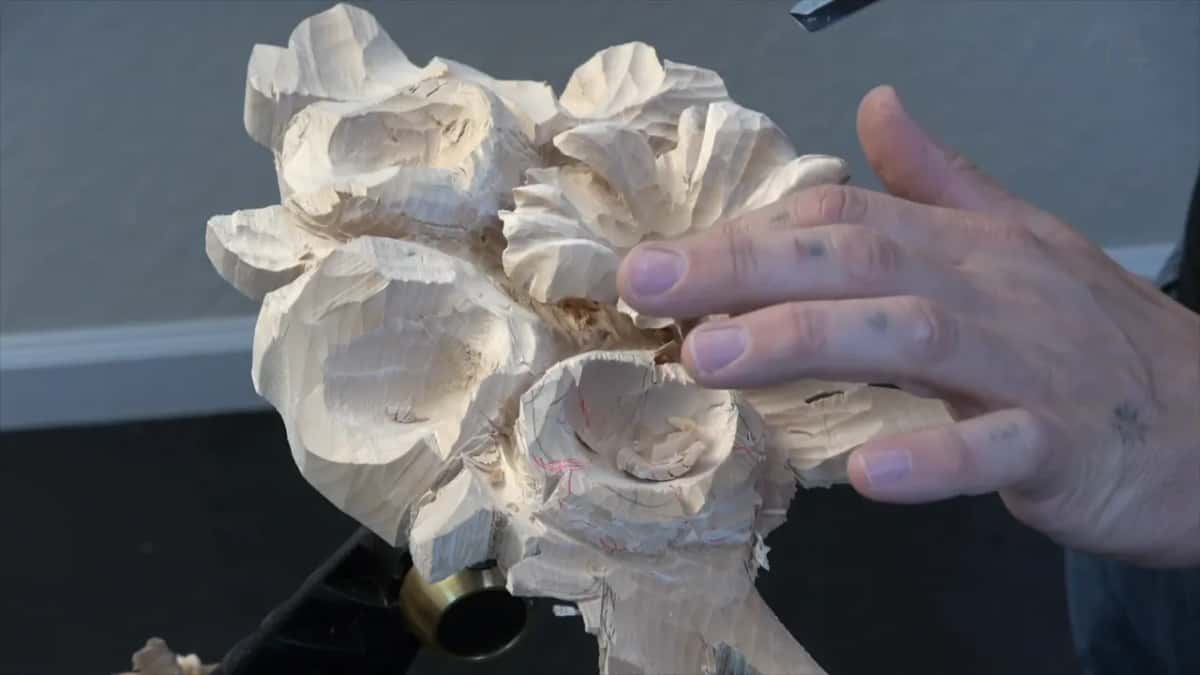 Hand braced away from one narrow petal that has been undercut on two sides already and will break if anything pushes on it