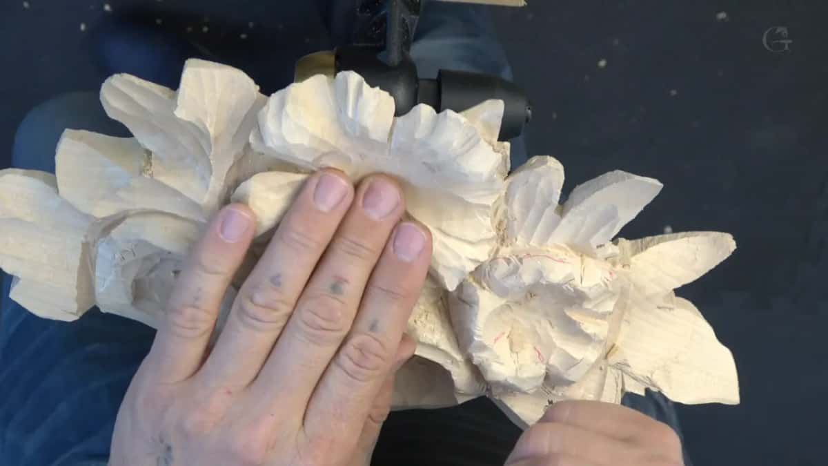Both hands flat on the panel, four flowers roughed, red pencil marks over on one of them