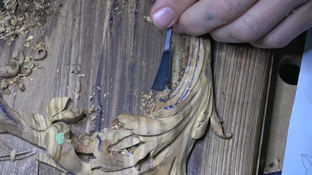 A flat blade shaves along the seam where the olive meets the lid, fine dust gathering against it