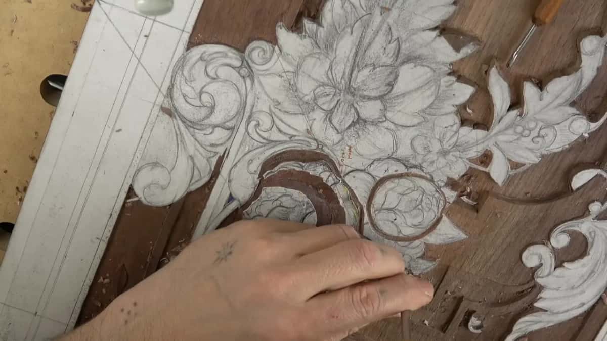 Flat palm resting over the half carved bloom while the rest of the corner waits under pencil