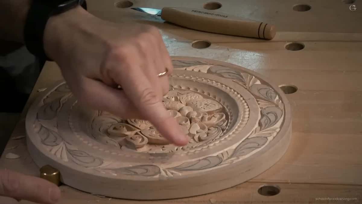 In a low side view, a finger points at the center, and a knife waits on the bench behind