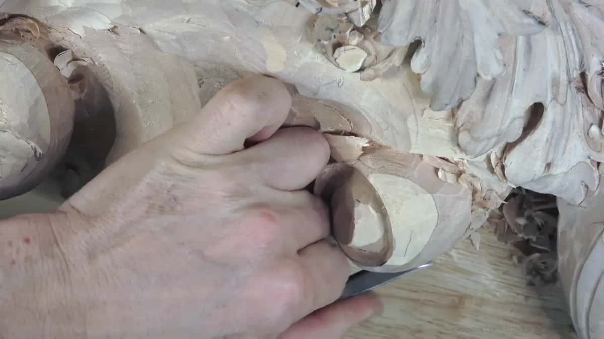 Fingers hold a flat blade low against the pale round end.